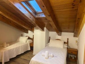 two beds in a room with wooden ceilings at Apartamento Dúplex Vistas al Valle de Incles Orenetes WiFi in Soldeu