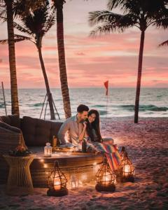 a man and a woman sitting on a table on the beach at Minh Phu Quoc lodge beach swimming pool in Phú Quốc