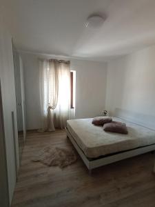 um quarto branco com uma cama e uma janela em A casa di Gigi em Tione di Trento
