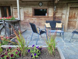 a patio with chairs and a table and some flowers at Traditional Chalet with some luxurious features in Troistorrents