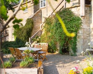a patio with a table and chairs in front of a building at The Coach House at Jervaulx in Ripon