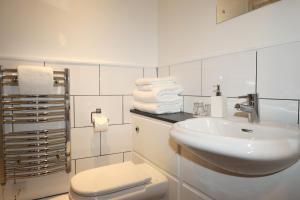 a bathroom with a sink and a toilet and towels at The Olde Kings Arms in Hemel Hempstead