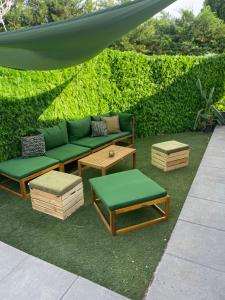 a patio with a green couch and ottomans and tables at Villa Pierre et Mer, maison 6 personnes a deux pas des plages in Hyères