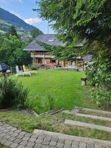 a yard with a house and a bench and grass at Traditional Chalet with some luxurious features in Troistorrents