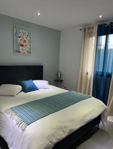 een slaapkamer met een groot bed en blauwe gordijnen bij Villa Cap Noir piscine chauffée avril à octobre in Saint-Joseph