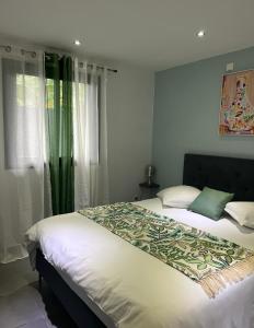 - une chambre avec un lit doté de draps blancs et de rideaux verts dans l'établissement Villa Cap Noir piscine chauffée avril à octobre, à Saint-Joseph