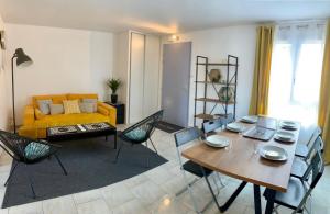 a living room with a yellow couch and a table and chairs at Appartement Eco 6 personnes in Magny-le-Hongre