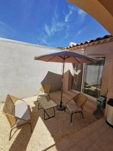 - une terrasse avec 2 chaises et un parasol dans l'établissement Studio neuf proche Camargue, à Gallargues-le-Montueux