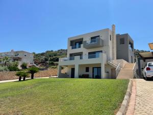 a large white house with a grassy yard at PENEMA VILLA in Hersonissos