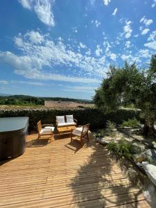 eine Terrasse mit zwei Stühlen und einer Bank auf einem Holzdeck in der Unterkunft Chambre d'hôtes avec Jacuzzi Ventoux Cocoon in Bédoin