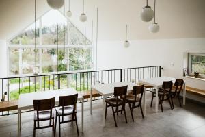 uma sala de jantar com mesas e cadeiras brancas e uma grande janela em Belsőörs - ház lélekkel em Felsőörs