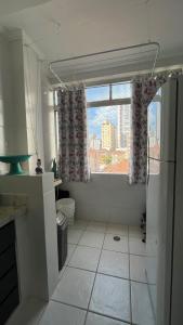 eine Küche mit einem Fenster und einem weißen Fliesenboden in der Unterkunft Apartamento lindo, Pet friendly, todo reformado no Canal 1 in Santos