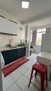eine weiße Küche mit einem roten Stuhl in einem Zimmer in der Unterkunft Apartamento lindo, Pet friendly, todo reformado no Canal 1 in Santos