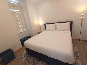 a bedroom with a large white bed with a window at FAMILY APARTAMENT I in Coimbra