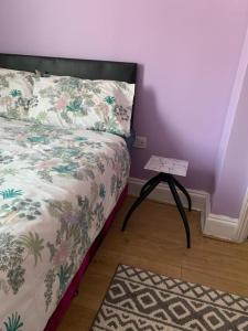a bedroom with a bed with a table next to it at Your Perfect HomeStay in Ilford