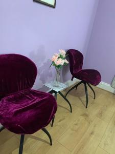 three purple chairs and a vase with flowers on a table at Your Perfect HomeStay in Ilford