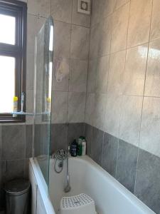 a bathroom with a white tub and a shower at Your Perfect HomeStay in Ilford