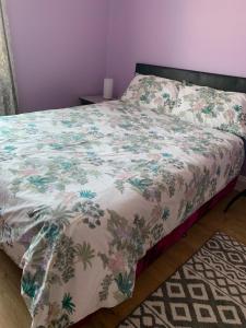 a bedroom with a bed with a floral bedspread at Your Perfect HomeStay in Ilford