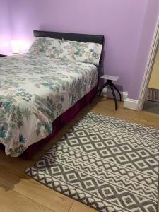 a bedroom with a bed and a rug on the floor at Your Perfect HomeStay in Ilford