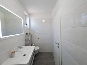 a white bathroom with a sink and a toilet at Holiday house SeaDream - 50 meters from the sea in Brodarica +25 photos