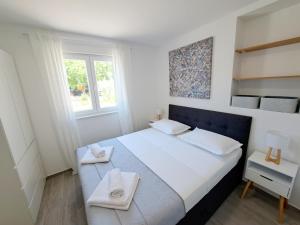 a white bedroom with a large bed with towels on it at Holiday house SeaDream - 50 meters from the sea in Brodarica