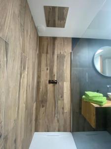 a bathroom with a shower with a wooden wall at Nid douillet et moderne in Beauménil