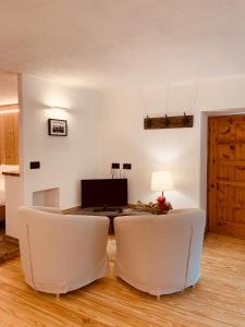 sala de estar con 2 sillas blancas y mesa en Lo Péyo - Le Four des Alpes, en Rhemes-Saint-Georges