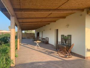 a porch with a wooden roof with chairs and a table at Vivi-Vendicari in Noto