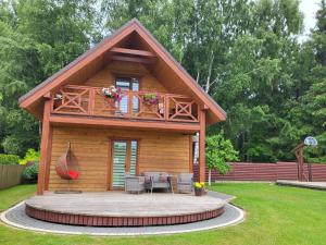 a log cabin with a table and chairs in a yard at Namelis mini-vila in Palanga +7 photos