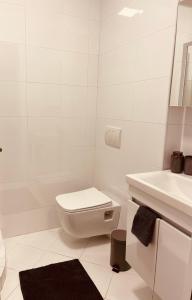 a white bathroom with a toilet and a sink at Central Apartment Prishtina in Pristina