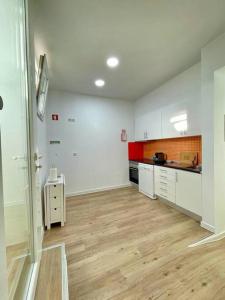 cocina grande con armarios blancos y suelo de madera en Casa da fortaleza en Sesimbra