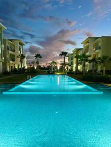 une grande piscine bleue en face de certains bâtiments dans l'établissement Cosy Apartment with sea view, à Sidi Rahal