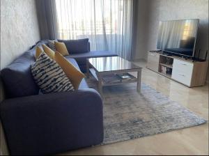 Sala de estar con sofá azul y mesa de centro en Cosy Apartment with sea view en Sidi Rahal