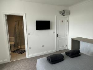 a room with a tv on a wall with two pillows at Sunny Modern, 1 Bed Flat, 15 Mins Away From Central London in Hendon