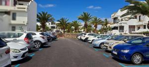 una fila di auto parcheggiate in un parcheggio di El Gueco Holiday Apartment a Costa Teguise