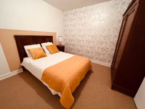 1 dormitorio con 1 cama con manta naranja en Le CASTELOU d'IDA, en Saint-Julien-Gaulène
