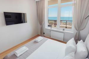 Schlafzimmer mit einem Bett, einem Fenster und einem TV in der Unterkunft Luxury Apart Arcadia in Odessa