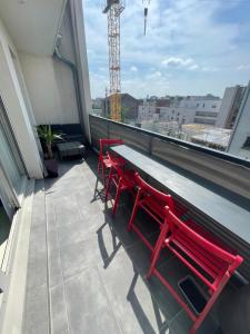 a balcony with red chairs and a table on a building at F4 lumineux proche du stade de France in Saint-Denis