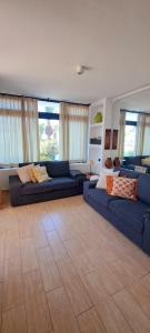 duży salon z niebieskimi kanapami i oknami w obiekcie El Gueco Holiday Apartment w Costa Teguise