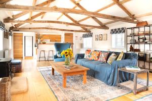 The Coach House at Jervaulx في ريبون: غرفة معيشة مع أريكة زرقاء وطاولة