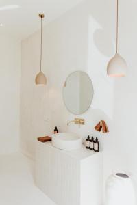 a white bathroom with a sink and two pendant lights at The Hut Hut in Uluwatu