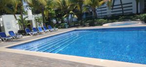 里奧阿托的住宿－Terrazas de Playa Blanca 1B，一个带蓝色椅子和棕榈树的大型游泳池