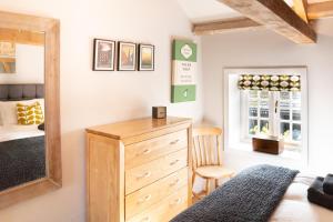 a bedroom with a wooden dresser and a mirror at The Coach House at Jervaulx in Ripon