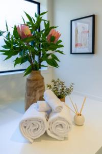 a bathroom counter with towels and a vase with flowers at Beautiful Gem by Hagley Park, Central City Chch in Christchurch