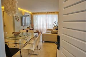 a dining room and living room with a glass table at TERRAMARIS - APARTAMENTO PÉ NA AREIA in Aquiraz