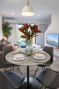 a dining room table with chairs and a vase of flowers at Beautiful Gem by Hagley Park, Central City Chch in Christchurch