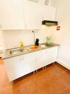 a kitchen with white cabinets and a sink at Beautiful Apartment near Carcavelos Beach in Parede