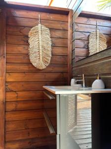 baño con lavabo y pared de madera en Bungalow avec jacuzzi privatif en Sainte-Rose