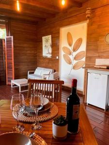 a wooden table with wine glasses and a bottle of wine at Bungalow avec jacuzzi privatif in Sainte-Rose