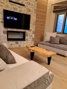 sala de estar con TV en una pared de piedra en Villagio inn Suite & Spa, en Soúlion